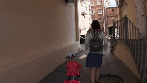 Mother goes through the arch with her daughter on a tricycle, slow motion. Stock Footage 77019911
