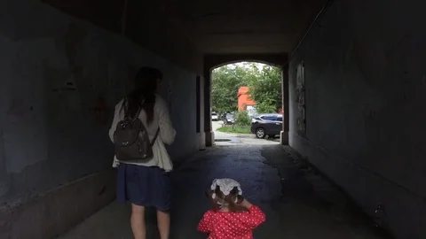 Mother goes through the arch with her daughter on a tricycle, slow motion. Stock Footage
