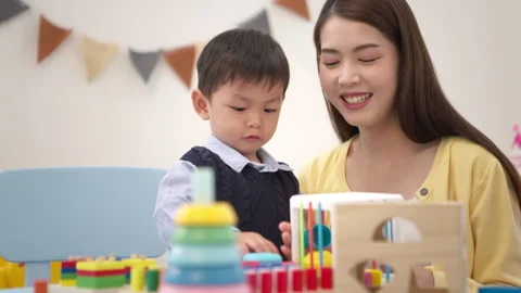 Mother guiding a child while playing educational toys Stockbeeldmateriaal 339555257