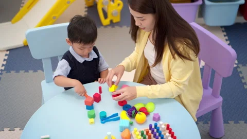 Mother guiding a child while playing educational toys Stock Footage 339555610