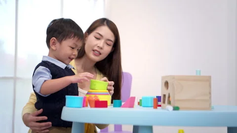 Mother guiding a child while playing educational toys Stock Footage 339555681