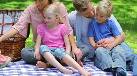 A mother handing a slice of watermelon each to her children and a sandwich to Stock Footage 10816099