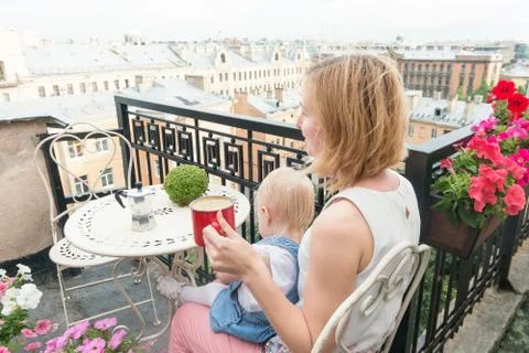 Mother having coffee break while sitting on balcony with a baby Stock Photos