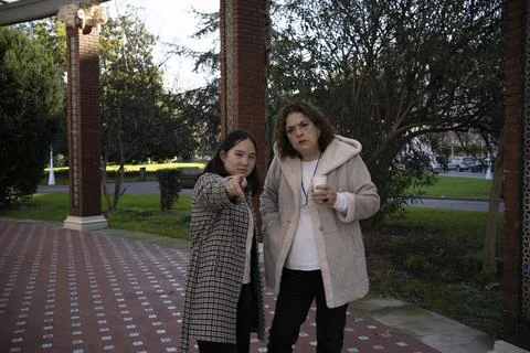 Mother having a coffee while her asian daughter pointing to the front. Stock Photos