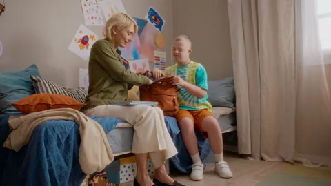 Mother Helping Boy with down Syndrome Packing Backpack for School Stock Footage 337562508