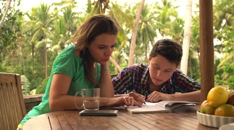 Mother helping her son doing homework by the table on terrace HD Stock Footage 42984017