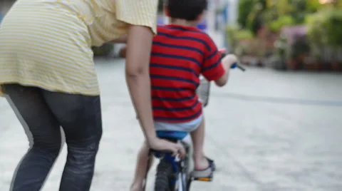 Mother helping her son training in bicycle Stockbeeldmateriaal 47750762