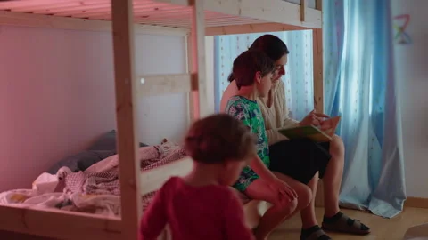Mother helping son develop reading skills before bedtime while toddler expl.. Stock Footage 337398992