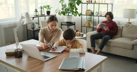 Mother helping son doing homework and father using digital tablet Stock Footage 145229744