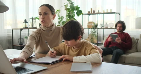 Mother helping son doing homework using laptop and father using digital tablet Stock Footage 145230584