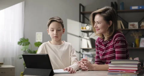 Mother helping son doing homework at home desk, studying online with digital Stock Footage 263928621