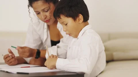 Mother helping son drawing on sofa at home Stock Footage 311059103