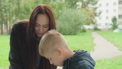 Mother helps her son prepare for school outside with encouragement. Supportive Stock Footage 335312200