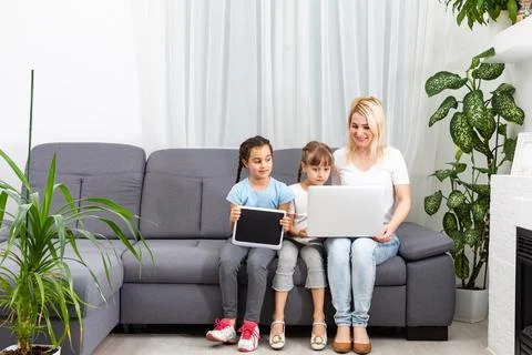Mother helps two daughters study online, using tablet and laptop when studying. 스톡 사진