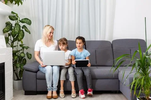 Mother helps two daughters study online, using tablet and laptop when studying. 스톡 사진