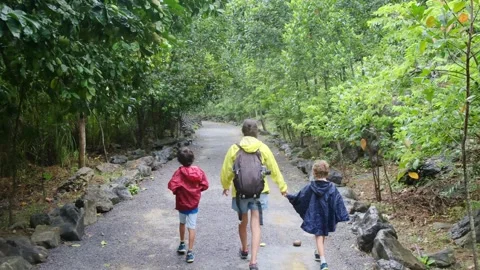 Mother, her backpack-clad children, and their colorful raincoats 库存影片 252036094