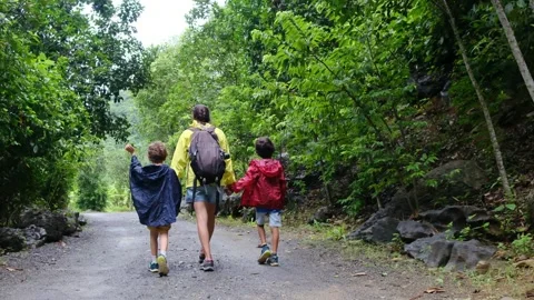 Mother, her backpack-clad children, and their colorful raincoats Stock Footage 252036183