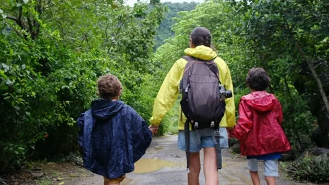 Mother, her backpack-clad children, and their colorful raincoats Video stock 252036206