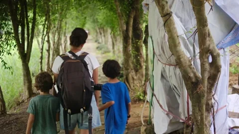 Mother, her backpack-clad children, and their colorful raincoats Stock Footage 252036261