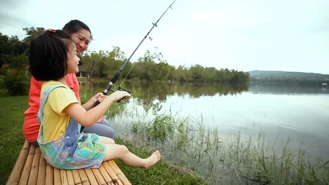 Mother with her daughter side by while fishing at lake. Concept of connecting Stock Footage 96586294