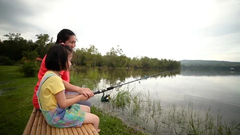Mother with her daughter side by while fishing at lake. Concept of connecting Stock Footage 96661712