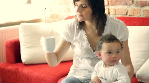 Mother with her son sitting on sofa and drinking coffee, dolly shot Stock Footage