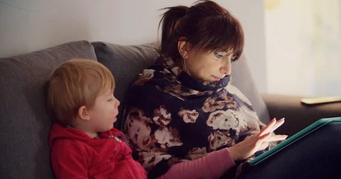 Mother with her son using tablet on sofa at home Stock Footage 103387465