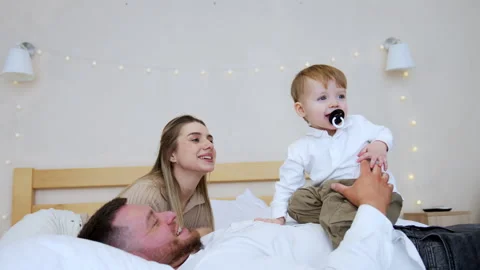 Mother hold a pacifier with her lips and baby boy reaches to get it with his mou Stock Footage 301896793