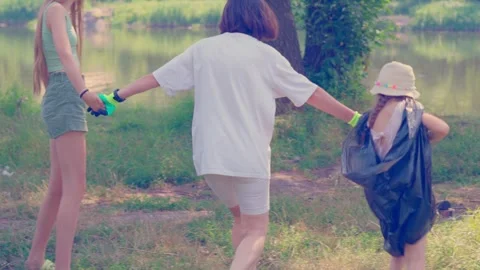 Mother Holding Hands with Two Daughters While Cleaning Plastic Waste from Stock Footage 340464600