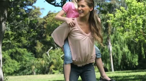 Mother holding her daughter on her back Stock Footage