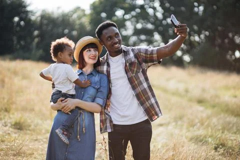 Mother holding son on hands while father taking selfie Stock Photos