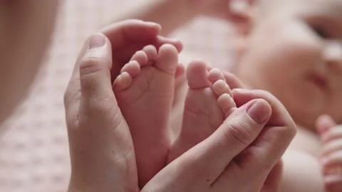 Mother is holding the tiny feet of newborn baby Stock Footage 150144979