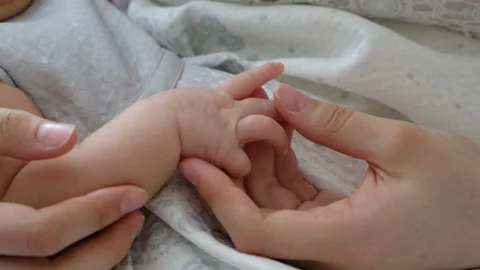 Mother holding tiny newborn baby's hands, close up Stock Footage 107553367