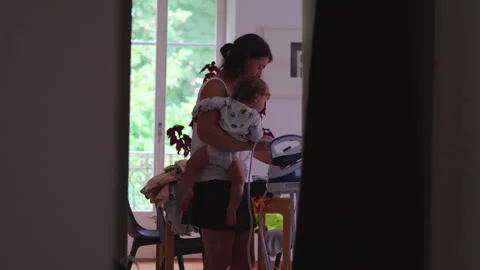 Mother holding toddler while ironing clothes at home multitasking childcare.. Stock Footage 335702987