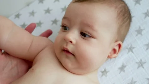 Mother holds her son's hand and the baby boy lying on his back Stock Footage