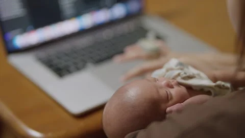 Mother holds newborn while working on laptop Stock Footage 340312051