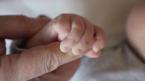Mother holds tiny hand of newborn baby girl in bedroom Stock Footage 196675731