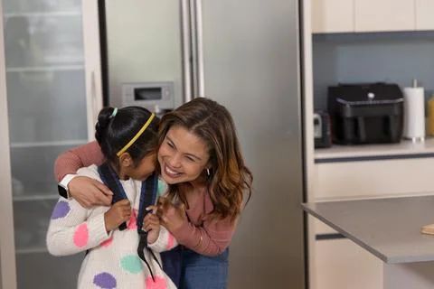 Mother hugging child in kitchen with backpack causing animated schedule over bag Stock Photos