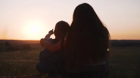 Mother hugs son pointing at sunset. Silhouette of family watching sunset Stock Footage 342604552