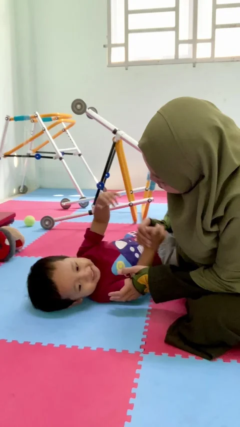 A mother interacting with a young child on a play mat Stock Footage 344918655
