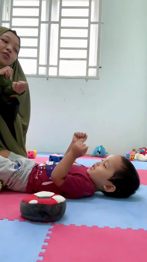 Mother interacting with a young child on a play mat Stock Footage 344918697