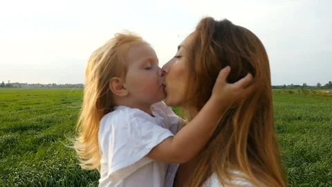 Mother with kid walking on green fields. Child caressing and kissing her mom Stock Footage 101373183