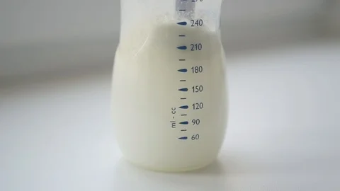 Mother in the kitchen stirring baby food in a bottle, slowmotion shot Stock Footage