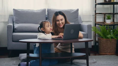 Mother with laptop computer teaching her kid to learn or study online Video stock 148365647