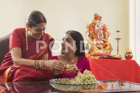 Mother in law teaching daughter in law how to make modaks on the occasion of Stock Photos