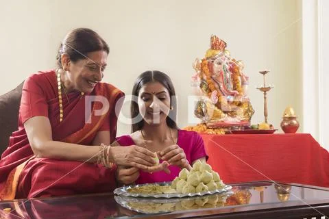 Mother in law teaching daughter in law how to make modaks on the occasion of Stock Photos