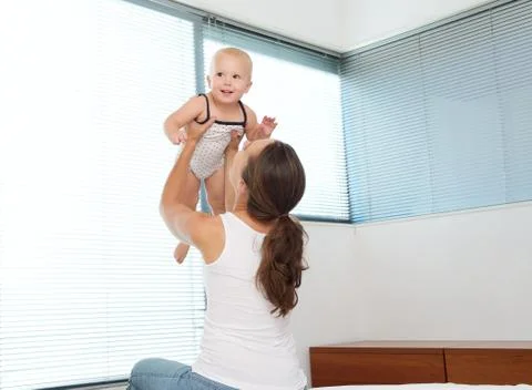 Mother lifting up and playing with a happy baby Stock Photos