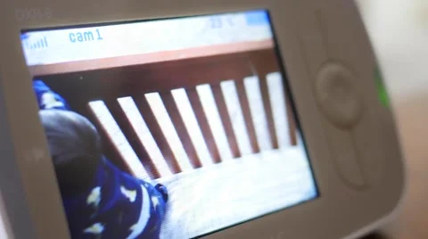 Mother lifts baby out of crib seen through monitor Stock Footage