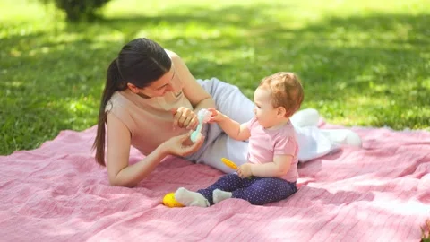 Mother lying on a blanket and playing with her cute baby boy at the park. Vídeos de archivo 335814591