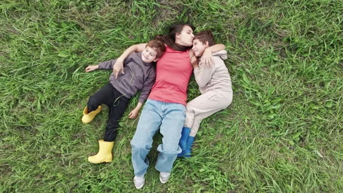 Mother lying in grass embracing two sons 스톡 동영상 315422045